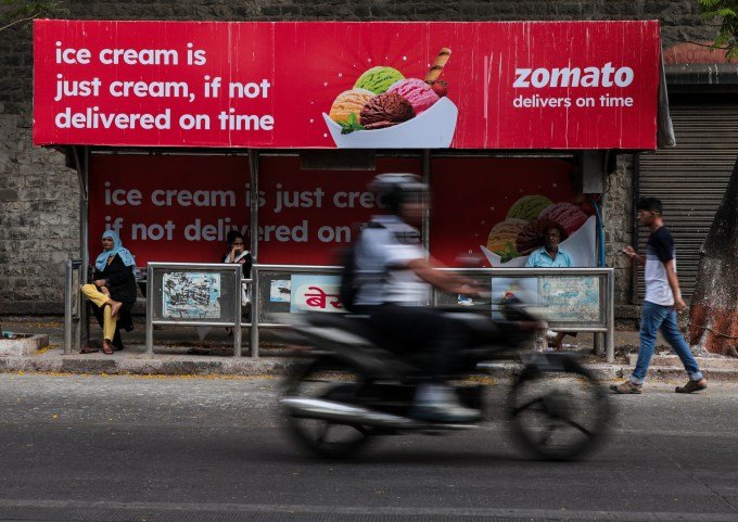 A man cycles by a bus stand showcasing Zomato, an Indian food delivery firm, in Mumbai, India, on June 9th, 2023.