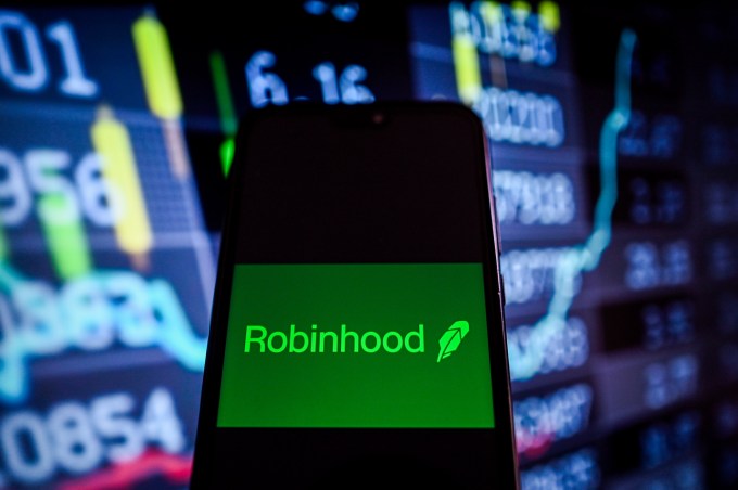Robinhood logo shown on a smartphone with stock market data in the background.