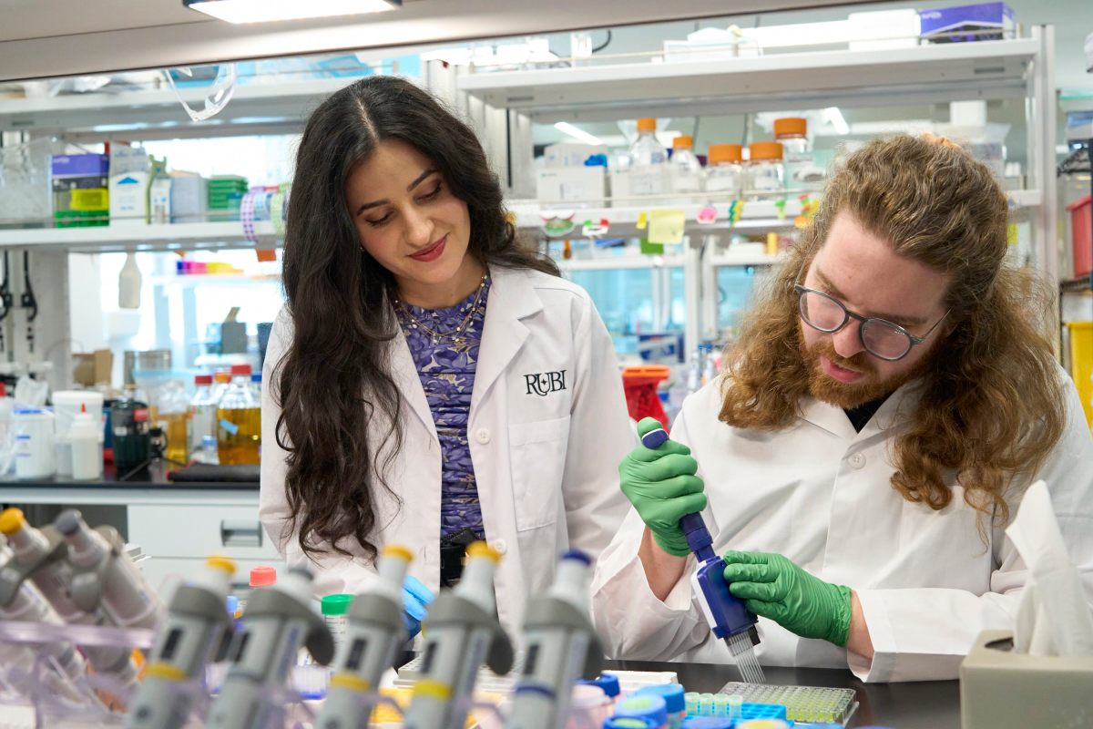 Two scientists pipette chemicals in a lab.