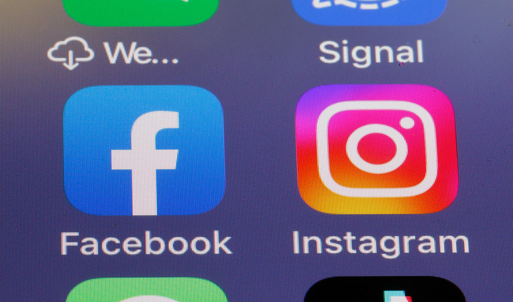 In this photo illustration, the logos of social media applications, Facebook and Instagram are displayed on the screen of an iPhone.