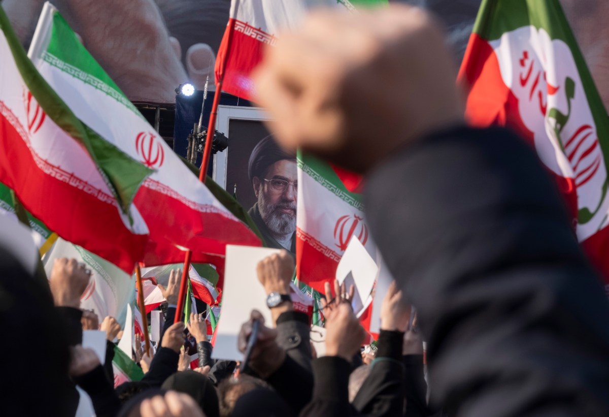 Iranian men shout anti-U.S. and anti-Israeli slogans in front of a portrait of Iran