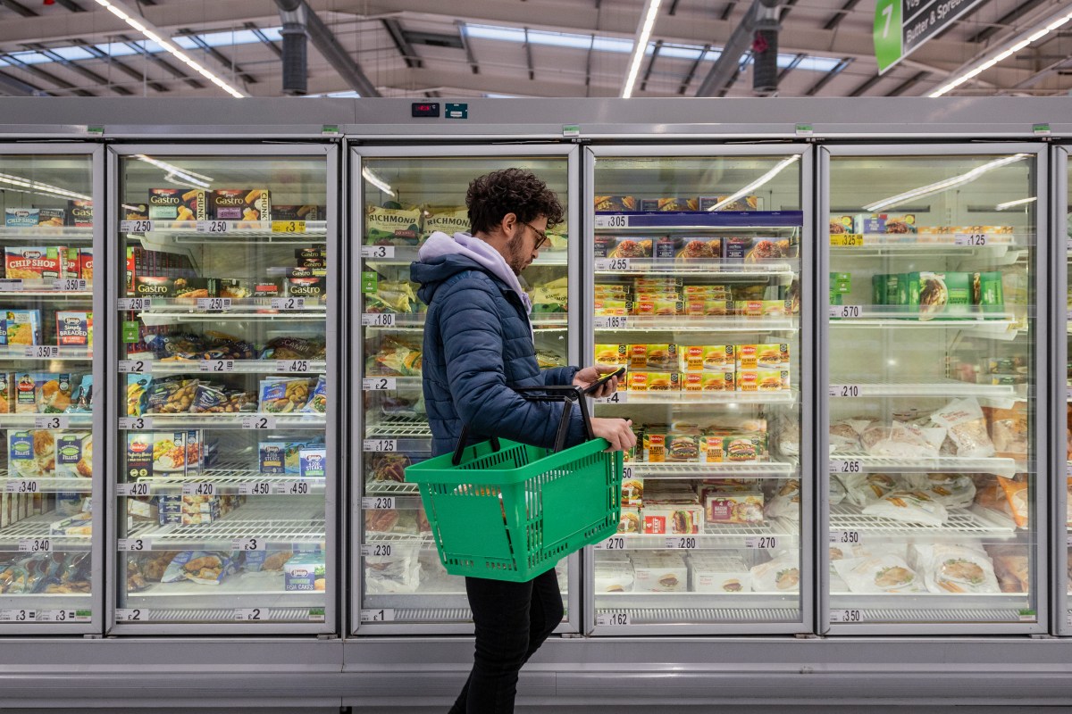 Man standing in front of refrigerator cases at a supermarket.